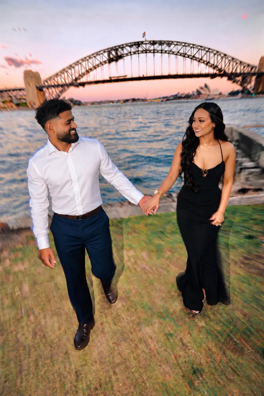 Jaz and Rianna walking hand in hand by the harbour at sunset